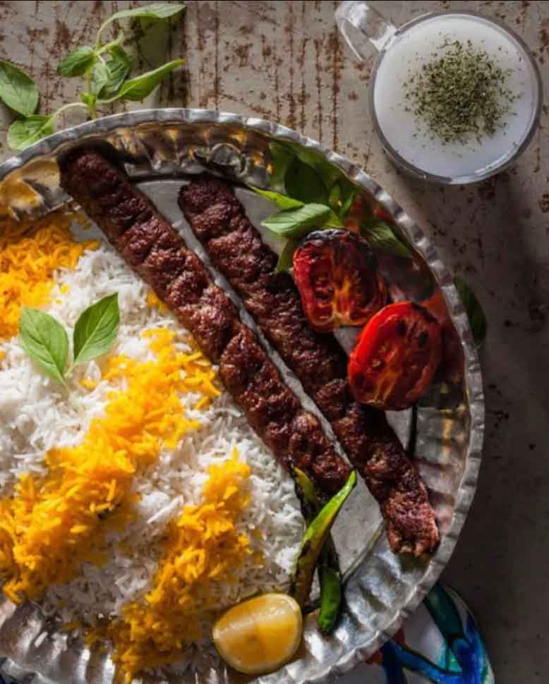  Persian Kebab Barg served with saffron rice, grilled tomatoes, lime, onion, green chili, and cherry tomatoes.