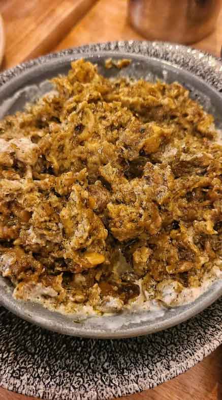 A bowl of Kashk-e Bademjan, a Persian eggplant dip topped with crispy fried onions and drizzled with kashk.